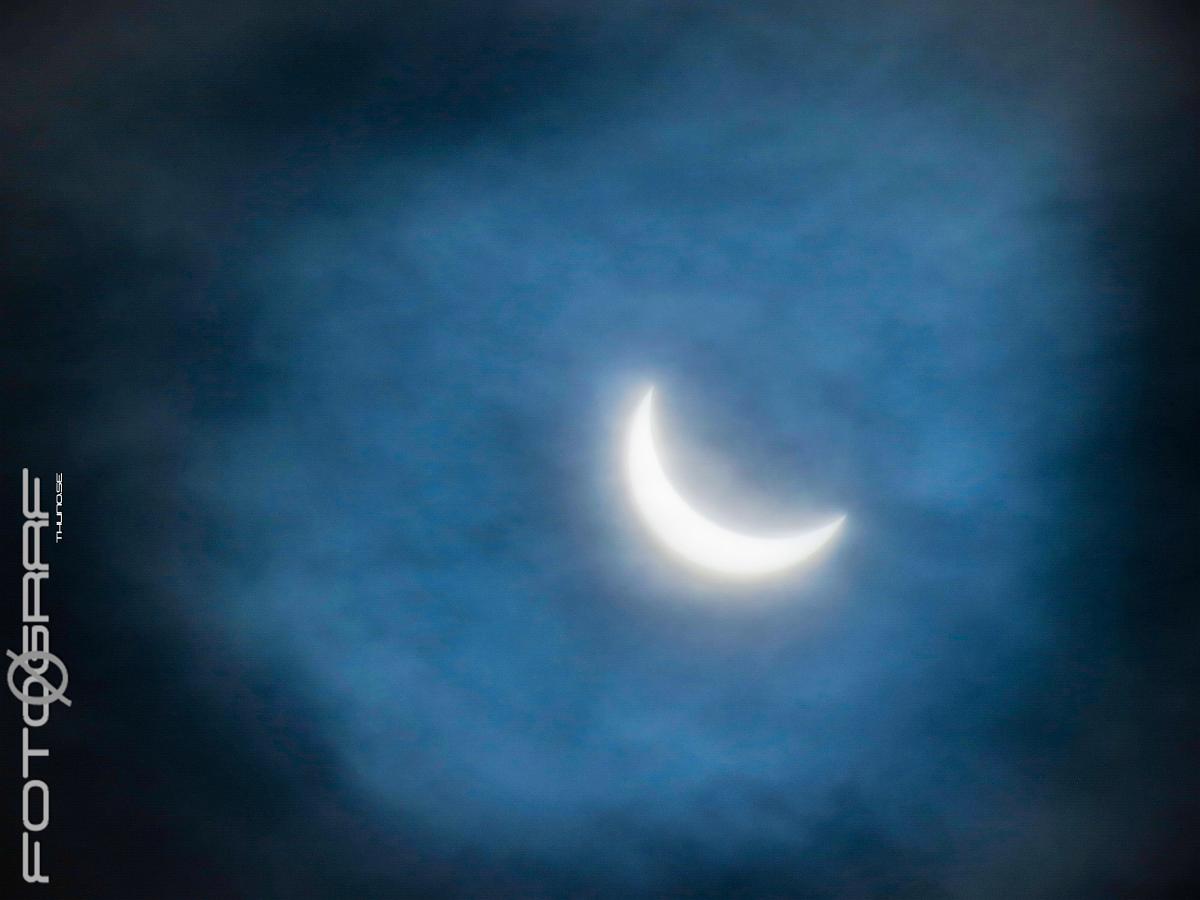 The moon and the sun 80% solar eclipse on a cloudy day.